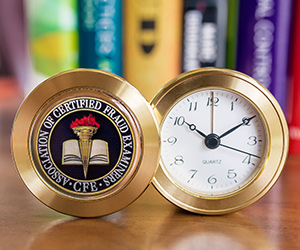 Laser engraged brass coin clock features an analog design and rotating faceplate with the ACFE Seal.